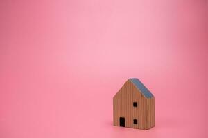 hout huis model- Aan roze achtergrond , beheren eigendom investering concept, banier achtergrond foto