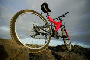 een rood berg fiets zit Aan top van een rotsachtig heuvel foto