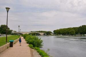 een Mens wandelen langs de rivier- bank in de buurt een brug foto