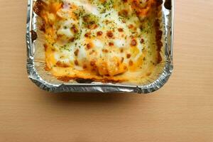 pasta makaroni saus keju of pasta Mac en kaas in de aluminium folie kom Aan de houten achtergrond foto