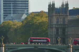 menigte wandelen door tour bus Aan beroemd Westminster brug naar paleis in stad foto
