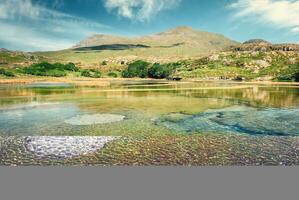 mooi landschap landschap met getij zwembaden Aan zanderig stranden omringd door groen bergen Bij zilver strand, Loughborough, provincie mayonaise, Ierland foto