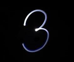 drie 3 blauw licht cijfer hand- schrijven over- zwart achtergrond. foto