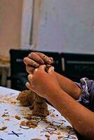 de handen van een kind wie is aan het doen activiteiten naar maken handwerk van klei of vaak gebeld een pottenbakkerij klasse en sommige van de resultaten foto