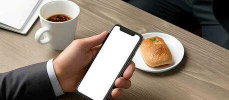 niet geïdentificeerd professioneel met blanco scherm mobiel aan het eten terwijl werken foto