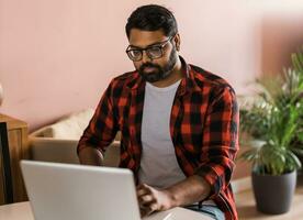 technologie afgelegen baan en levensstijl concept - gelukkig Indisch Mens in bril met laptop computer werken Bij huis kantoor foto