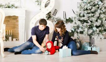 Kerstmis familie met baby opening geschenken. gelukkig glimlachen ouders en kind Bij huis vieren nieuw jaar foto