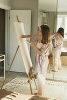 jong vrouw artiest schilderij Aan canvas Aan de ezel Bij huis in slaapkamer - kunst en creativiteit concept foto