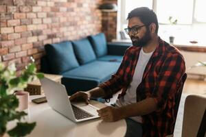 gelukkig Indisch Mens freelancer of ondernemer hebben video conferentie praten, werken van een afstand online Bij huis kantoor kopiëren ruimte - video telefoontje en verscheidenheid concept foto