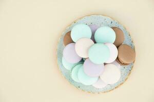 verschillend pastel kleuren gebakje macarons in bord top visie Aan een beige achtergrond foto