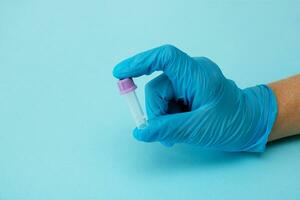 een gehandschoende hand- houdt een leeg test buis Aan een blauw achtergrond met kopiëren ruimte, modern diagnostiek foto