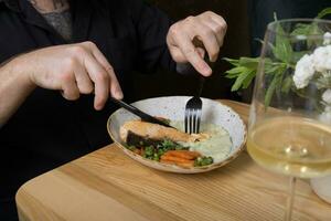 een jong Mens eet Zalm met groente puree Bij een restaurant tafel foto