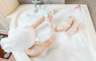 mooi meisje douchen en het wassen handen in bad. foto