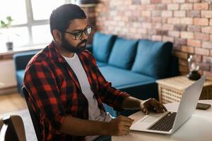 gelukkig Indisch Mens freelancer of ondernemer hebben video conferentie praten, werken van een afstand online Bij huis kantoor - video telefoontje en verscheidenheid concept foto