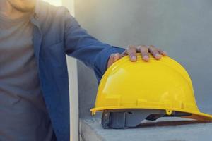 arbeidersarchitect die gele helm in bouwconstructie houdt foto