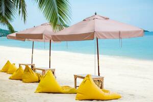 mooi visie van tropisch strand, Thailand. geel strand bed, Boon zak stoel en paraplu Aan wit zand voor ontspannende op zoek uit over- de blauw zee oceaan. rust uit in de vakantie concept. foto