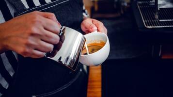 professioneel barista in koffie winkel maken gieten gestoomd melk in de koffie kop maken latte menu foto