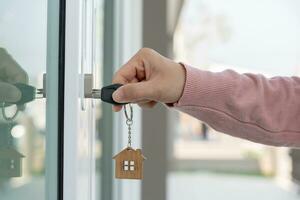 landheer sleutel voor ontgrendelen huis is aangesloten in de deur. tweede hand- huis voor huur en uitverkoop. eigenaar gebruik hand- ontgrendelen deur hypotheek voor nieuw huis, kopen, verkopen, renoveren, investering, baasje, landgoed foto