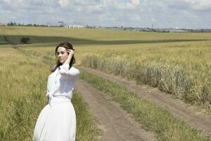 een vrouw in een wit jurk staand in een veld- foto