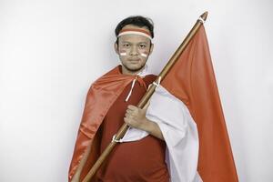 gelukkig glimlachen Indonesisch Mens Holding Indonesië's vlag naar vieren Indonesië onafhankelijkheid dag geïsoleerd over- wit achtergrond. foto