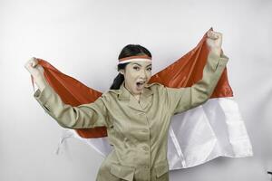 glimlachen regering arbeider vrouw Holding Indonesië's vlag geïsoleerd door wit achtergrond. pns vervelend khaki uniform. Indonesië's onafhankelijkheid dag concept. foto