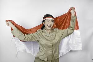 glimlachen regering arbeider vrouw Holding Indonesië's vlag geïsoleerd door wit achtergrond. pns vervelend khaki uniform. Indonesië's onafhankelijkheid dag concept. foto