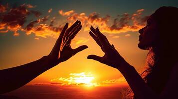handen in afdaling zonsondergangen achter verheven vrouw handen. silhouet concept foto