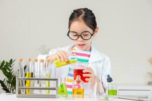 Aziatisch weinig meisje werken met test buis wetenschap experiment in wit klas foto