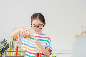Aziatisch weinig meisje werken met test buis wetenschap experiment in wit klas foto
