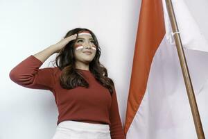 Indonesisch vrouw geven groet met trots gebaar terwijl Holding Indonesië's vlag. Indonesië's onafhankelijkheid dag concept. foto