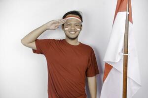 Indonesisch Mens geven groet met trots gebaar terwijl Holding Indonesië's vlag. Indonesië's onafhankelijkheid dag concept. foto