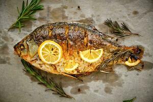 gekookt Aan perkament papier, gebakken vis met kruiden, citroen en rozemarijn. foto