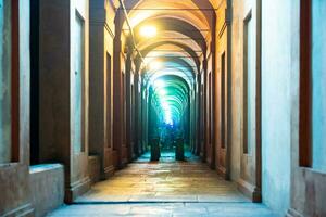 Bologna, Italië- juni 23, 2023-mensen wandeling Bij nacht onder de arcades leidend naar de heiligdom van san luca verlichte voor de eerste editie van de bologna arcades festival. foto