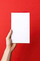 een menselijk hand- Holding een blanco vel van wit papier of kaart geïsoleerd Aan rood achtergrond. ai gegenereerd foto