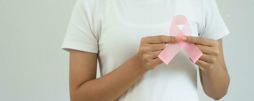 vrouw houden roze lint borst kanker bewustzijn. vrouw Gezondheid controleren bewustzijn. Internationale Dames dag en wereld kanker dag. teken kanker, symbolisch, Gezondheid zorg, ondersteuning patiënten, tijdig diagnose foto