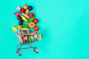 metaal boodschappen doen kar met fruit en groenten Aan een blauw achtergrond. speelgoed- miniatuur boodschappen doen trolley foto