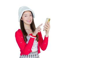 portret van mooi Aziatisch tiener meisje vervelend rood jurk en wit hoed gelukkig glimlach gebruik makend van smartphone terwijl werken geïsoleerd Aan wit achtergrond. foto