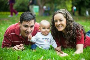 jong ouders hebben pret buitenshuis met hun zes maanden oud baby meisje. geluk concept. familie concept foto