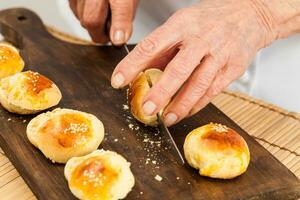 snijdend klein brood broodjes voor mini hamburgers. stap door stap voorbereiding van mini hamburgers. eigengemaakt mini hamburgers voor kinderen of voorgerechten. klein hamburgers. foto