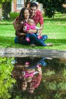 jong ouders hebben pret buitenshuis met hun zes maanden oud baby meisje. geluk concept. familie concept foto