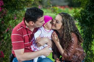 jong ouders hebben pret buitenshuis met hun zes maanden oud baby meisje. geluk concept. familie concept foto