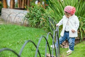 zoet jaar en een voor de helft baby meisje Bij de tuin in een mooi zonnig dag foto