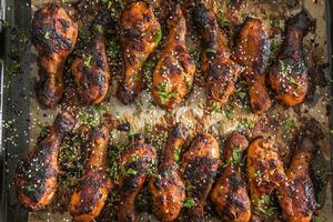 gegrild hicken poten bbq met specerijen kruiden en sesam Aan gebakken papier - top van visie. geroosterd gevogelte maaltijd in brander schotel foto