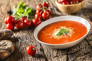 heet tomaat soep Parmezaanse kaas kaas en basilicum vertrekken Aan oud oal tafel foto