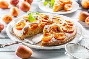 abrikoos taart Aan een wit bord, abrikozen, munt en gepoederd suiker Aan de keuken tafel foto