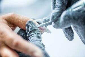 repareren oud gel nagels met een nagel Slijper in nagel studio - salon. nagels manicuren. foto