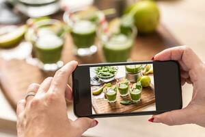 blogger vrouw maken foto van smoothie met cel telefoon