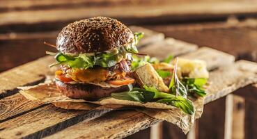 huis gemaakt smakelijk hamburger met spek ui kaas ane sla Aan houten doos foto