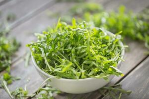 vers rucola salade in wit schotel Aan houten tafel foto