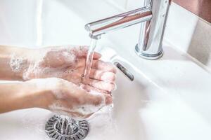 het wassen handen met water en vloeistof zeep in de badkamer. hygiëne antivirus concept foto